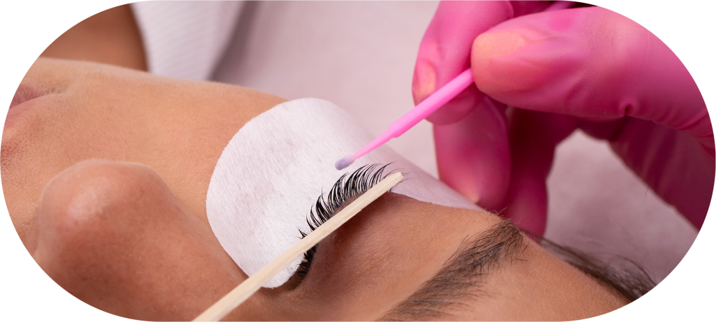 Profissional vestindo luvas realizando extensão de cílios